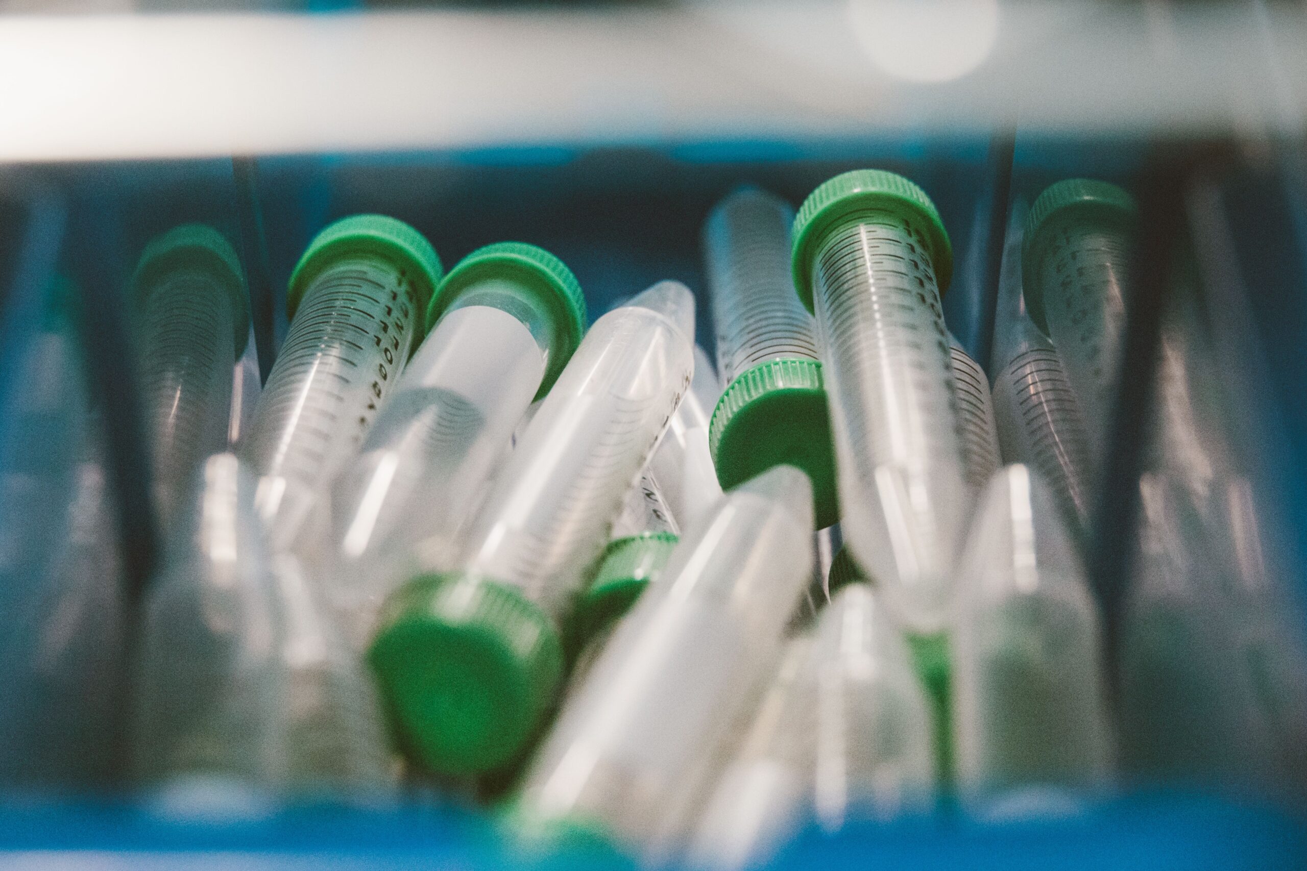 A collection of plastic laboratory test tubes with green caps in a tray, ideal for scientific themes.